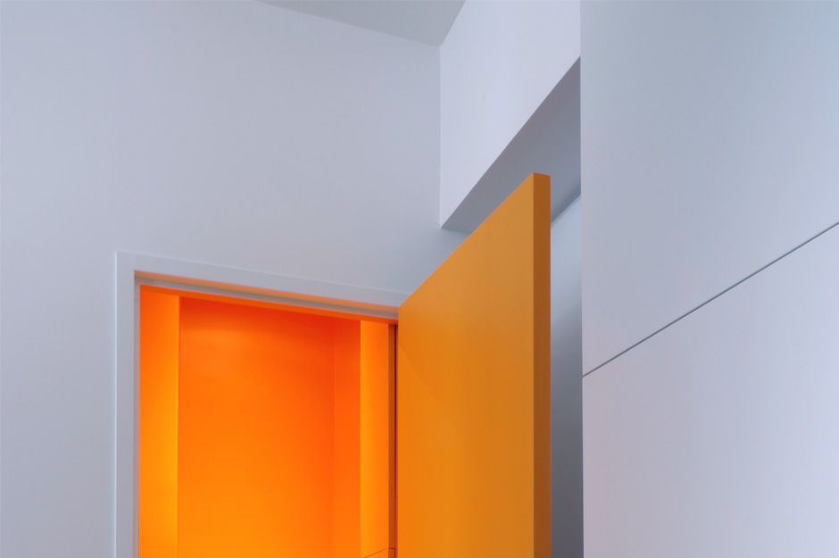Rénovation d'un appartement contemporain à Lyon avec un meuble central sur mesure. Détail des couleurs avec le wc orange.