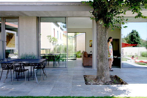 Extension contemporaine à Caliure et Cuire en ossature bois et parement ciment Viroc. Terrasse et salon dans le prolongement grâce à de larges baies coulissantes.